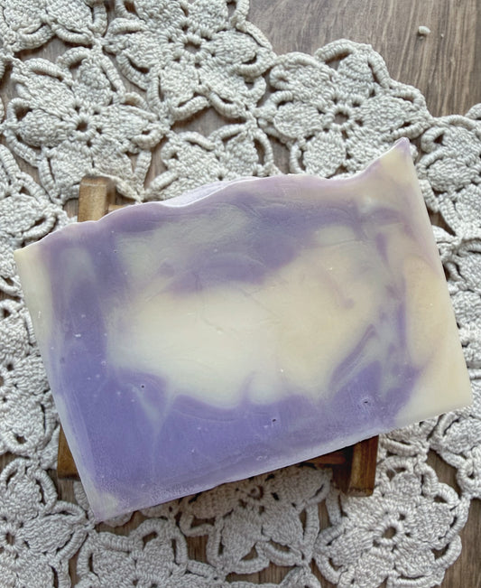A Berry Creme Natural Goat Milk Soap Bar by Lil Daisy Soaps sits on a wood dish on a lace doily.