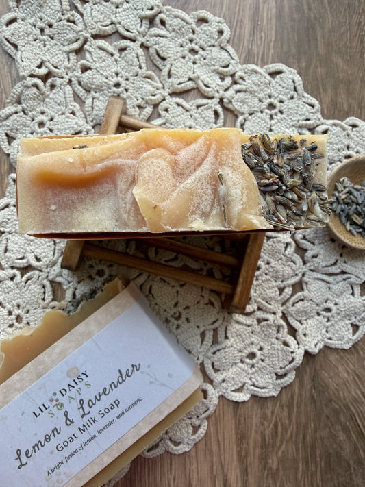 Lil Daisy Soaps Lemon & Lavender Goat Milk Soap Bar, topped with dried lavender, on a crocheted doily.