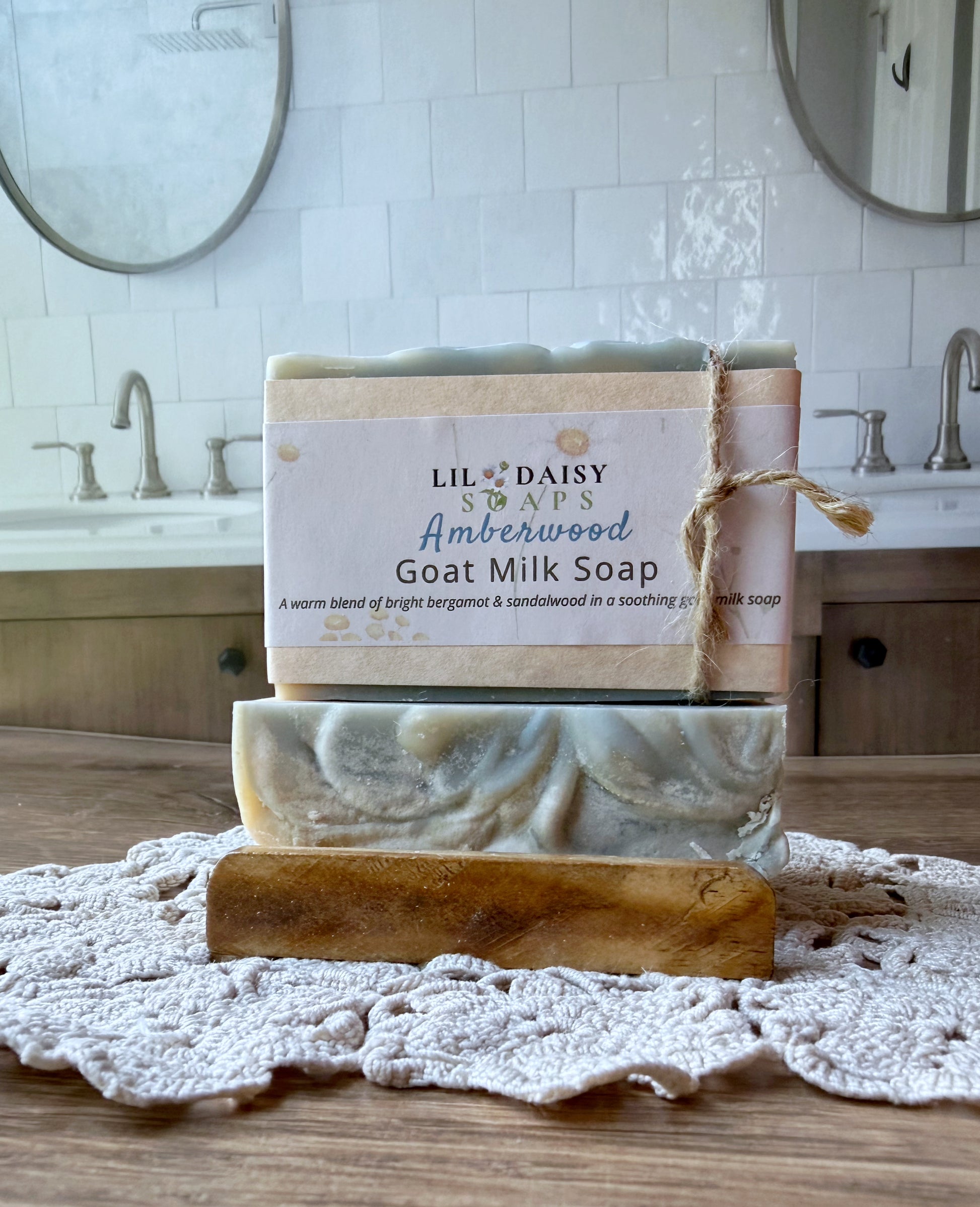 Lil Daisy Soaps Amberwood Natural Goat Milk Soap Bar rests on a crocheted mat in a rustic, handmade setting.