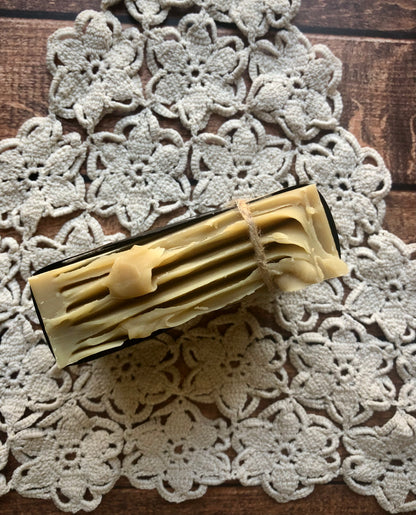 Lil Daisy Soaps Balsam & Fir Goat Milk Soap bar sits on a crocheted doily atop a wooden surface.