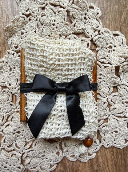 A Lil Daisy Soaps Bamboo Soap Ladder & Natural Fiber Soap Saver, tied with black ribbon on a lacy doily.