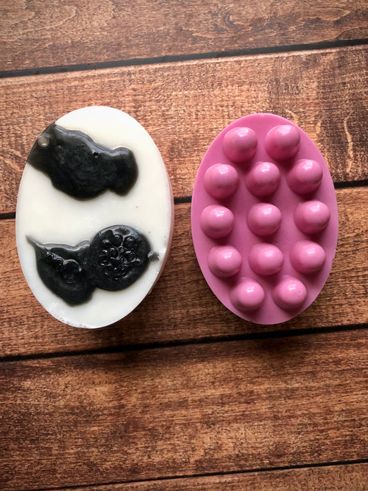 Two Daisys Cow Massage Bars by Lil Daisy Soaps, pink massage and goat milk, on a wooden surface.