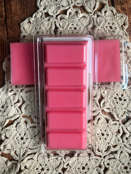 Two Lil Daisy Soaps Desert Blossom Wax Melt snap bars with floral scent on a lace doily over wood.