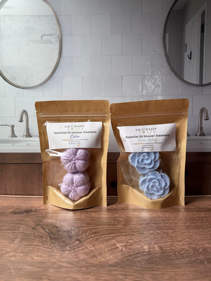 Two Lil Daisy Soaps Essential Oil Shower Steamers, incl. Lavender Chamomile, sit near two sinks.