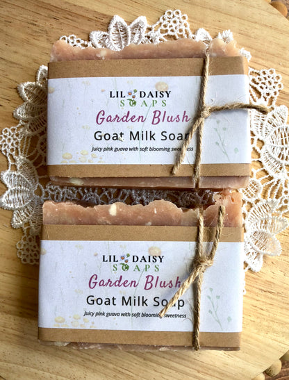 Two Lil Daisy Soaps Garden Blush Goat Milk Soap Bars sit on a lace doily on a wooden surface.