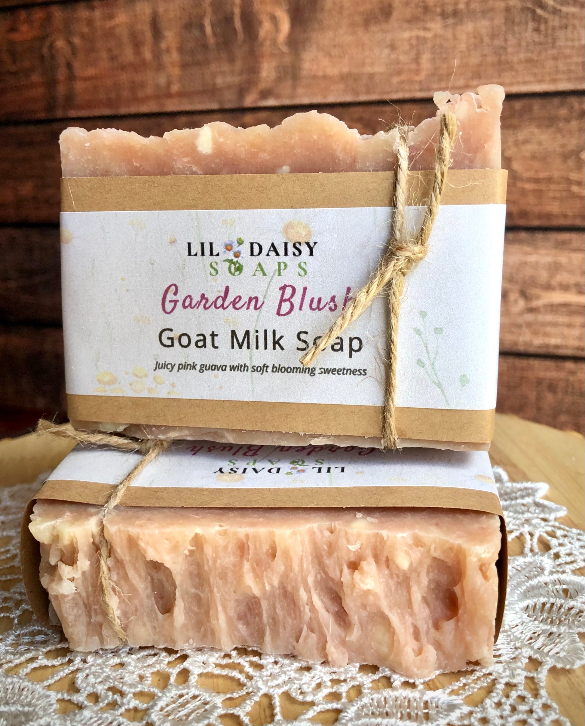 Two Lil Daisy Soaps Garden Blush Goat Milk Soap Bars, tied with twine, on a lace cloth.