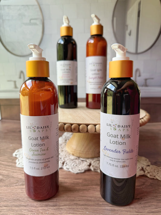 Four Lil Daisy Soaps Goat Milk Lotion bottles, lightweight daily moisturizers, displayed on a wooden stand.