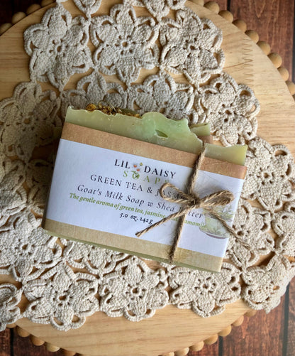 Lil Daisy Soaps Green Tea & Jasmine Goat Milk Soap with twine sits on a doily on wood.