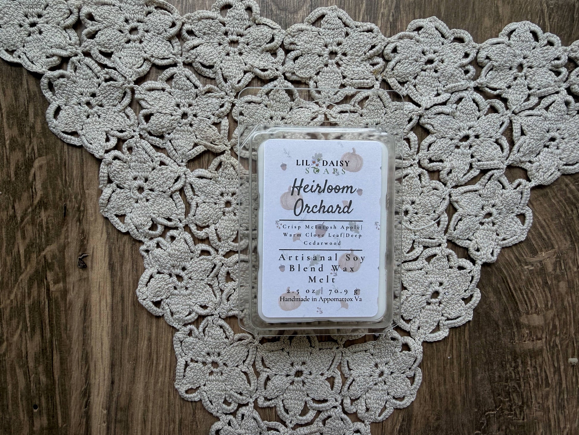 Heirloom Orchard soy wax melt by Lil Daisy Soaps, Macintosh apple scent, sits on lace atop wood.