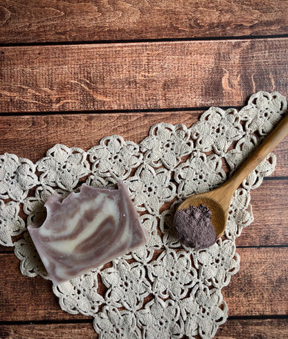 Lil Daisy Soaps Lavender Fields Natural Goat Milk Soap Bar with wooden spoon and powder on a crocheted doily.