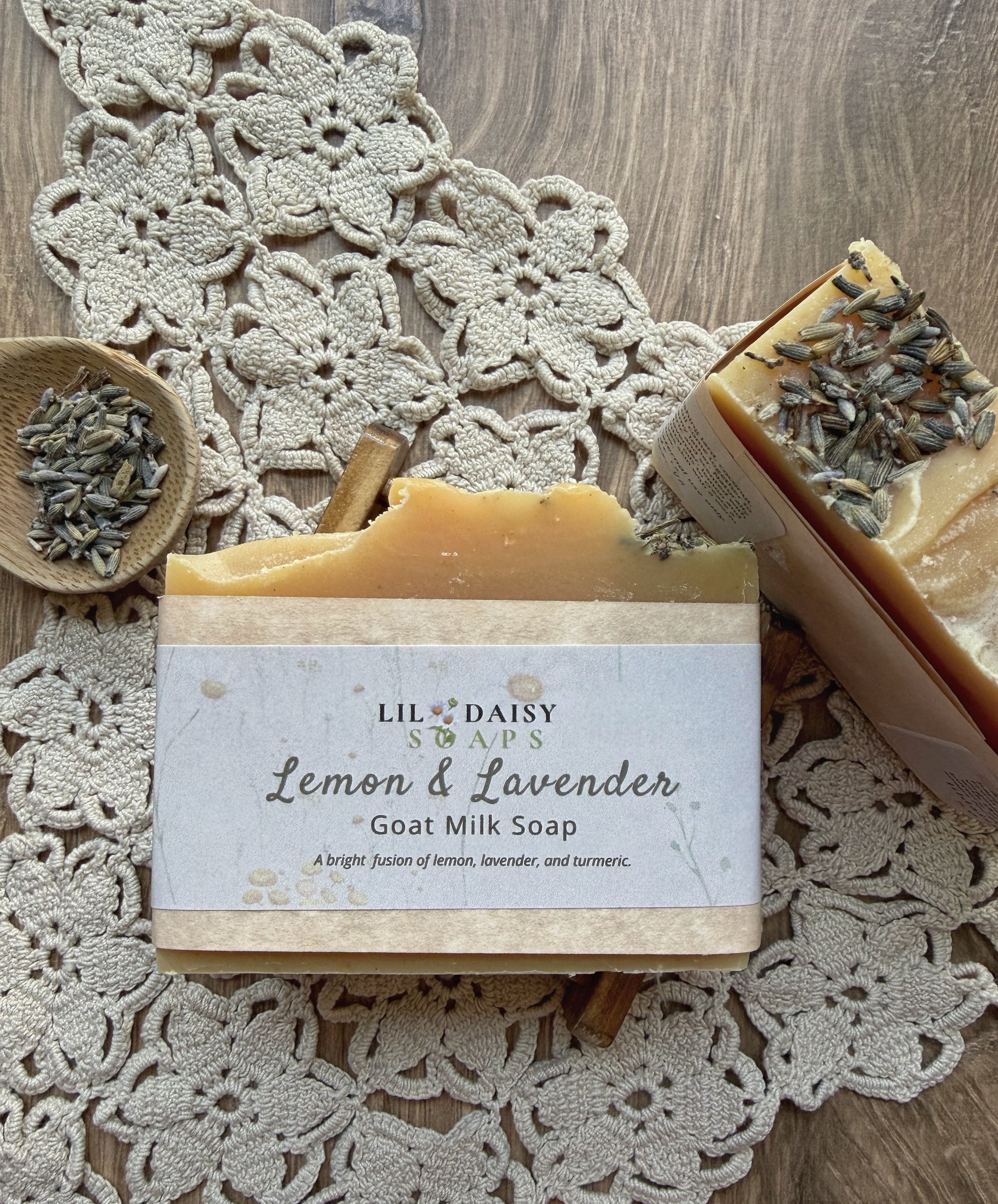 Two Lil Daisy Soaps Lemon & Lavender Goat Milk Soap Bars on lace with dried lavender, cinnamon, and turmeric soap.