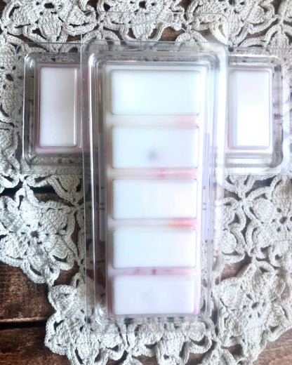 The Lil Daisy Soaps Meadow Flowers Wax Melt-Long Lasting Snap Bar sits on a lace doily and wood surface.