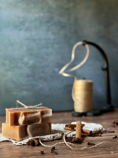 Lil Daisy Soaps’ Pumpkin Cinnamon Goat Milk Soap bars with twine, spices, and a blurred twine spool in view.