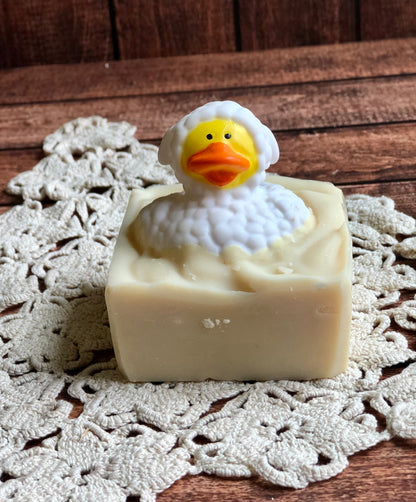Lil Daisy Soaps Rubber Ducky Goat Milk Soap bar with a duck design on a doily and wood surface.