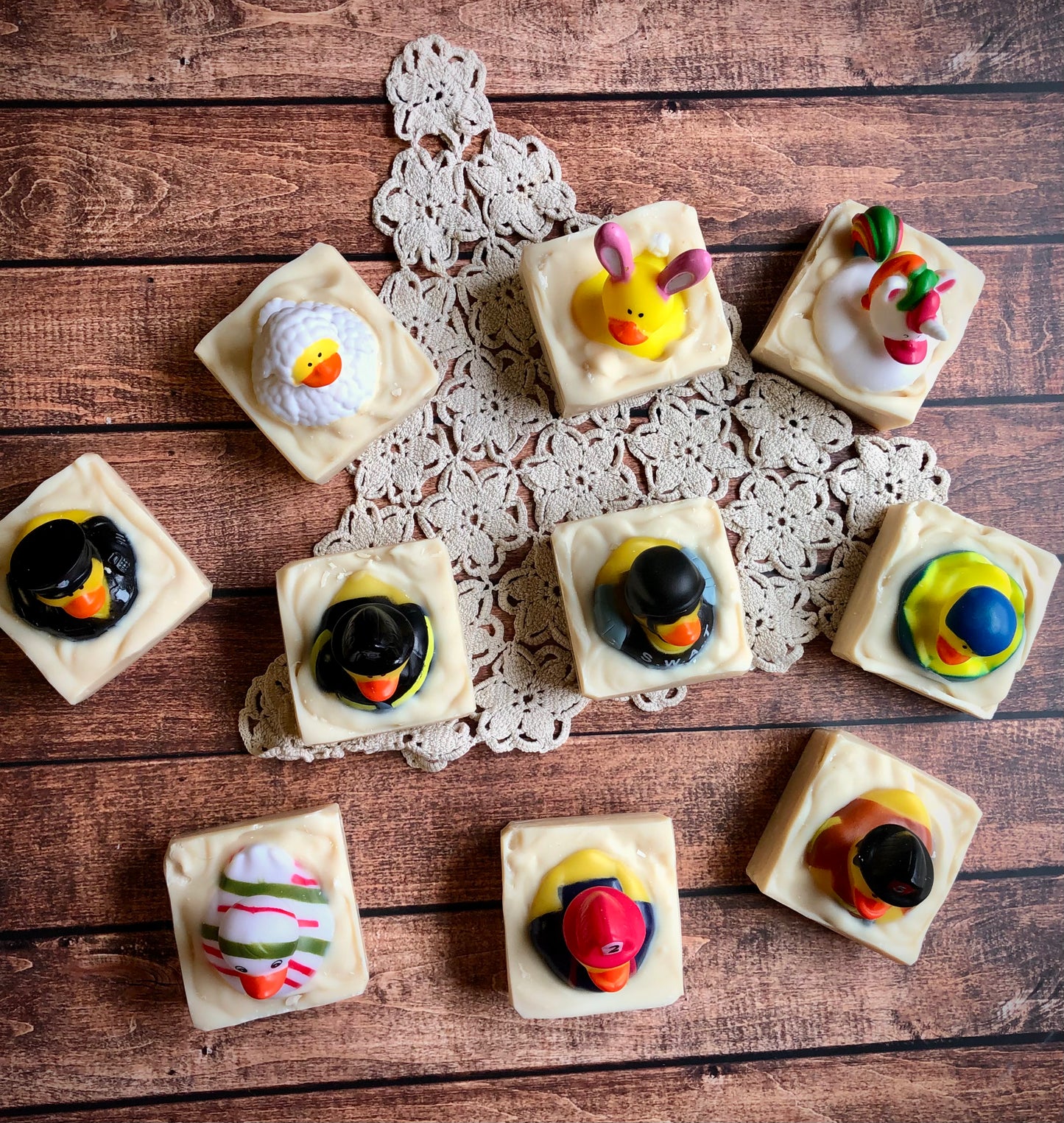 Lil Daisy Soaps Rubber Ducky Goat Milk Soap bars topped with colorful ducks, arranged on a doily.