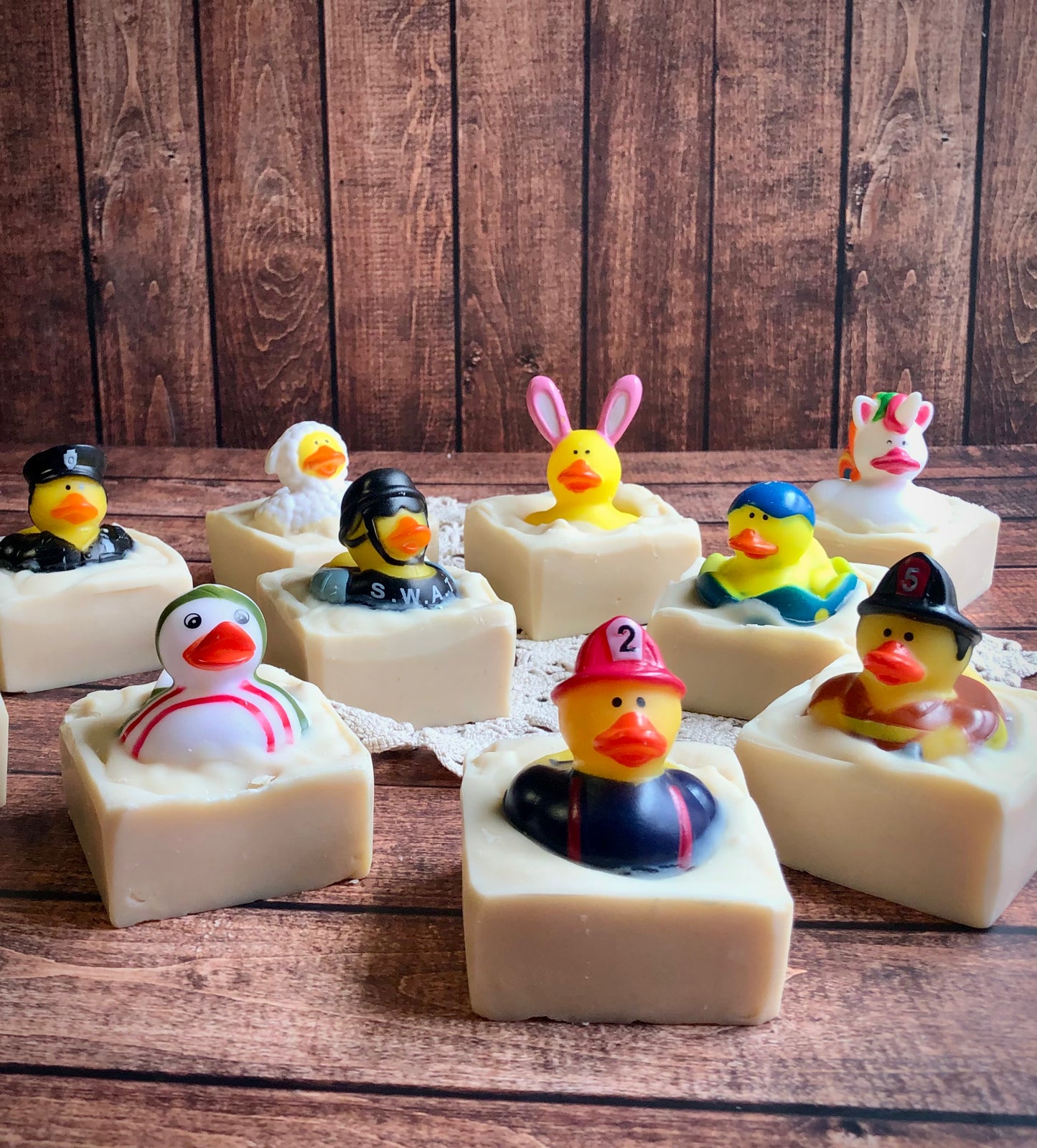 Nine Lil Daisy Soaps Rubber Ducky Goat Milk Soaps with ducks in costumes on a wooden surface.