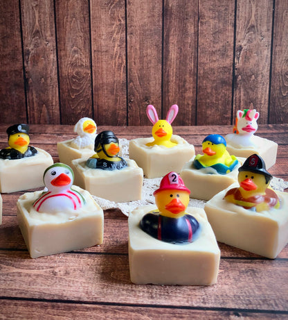 Nine Lil Daisy Soaps Rubber Ducky Goat Milk Soaps with ducks in costumes on a wooden surface.