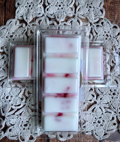 Lil Daisy Soaps Spiced Apple Crisp Snap Bar Wax Melt with red streaks on a crocheted doily.