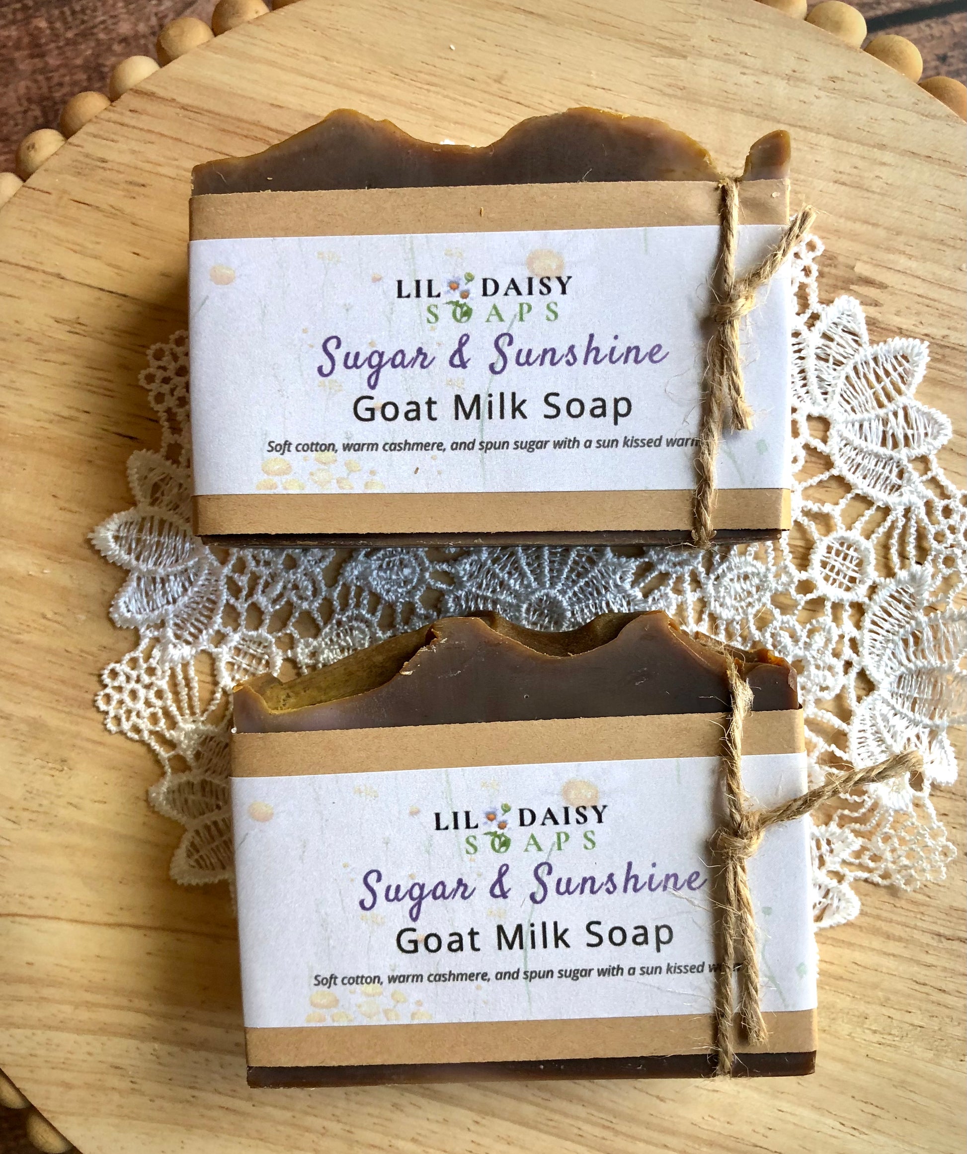 Two Sugar & Sunshine Goat Milk Soaps by Lil Daisy Soaps on a lace doily and wooden surface.