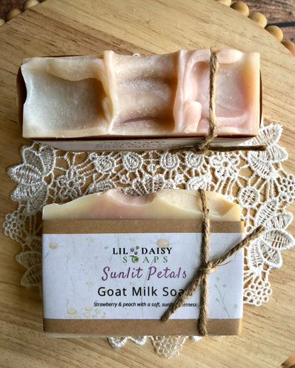 Two handmade Lil Daisy Soaps Sunlit Petals Goat Milk Soap bars rest on a lace doily.