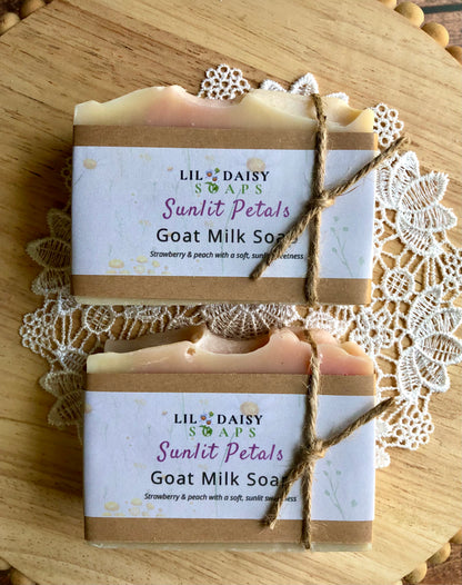 Two Sunlit Petals Goat Milk Soaps by Lil Daisy Soaps with twine, on a lace doily atop wood.
