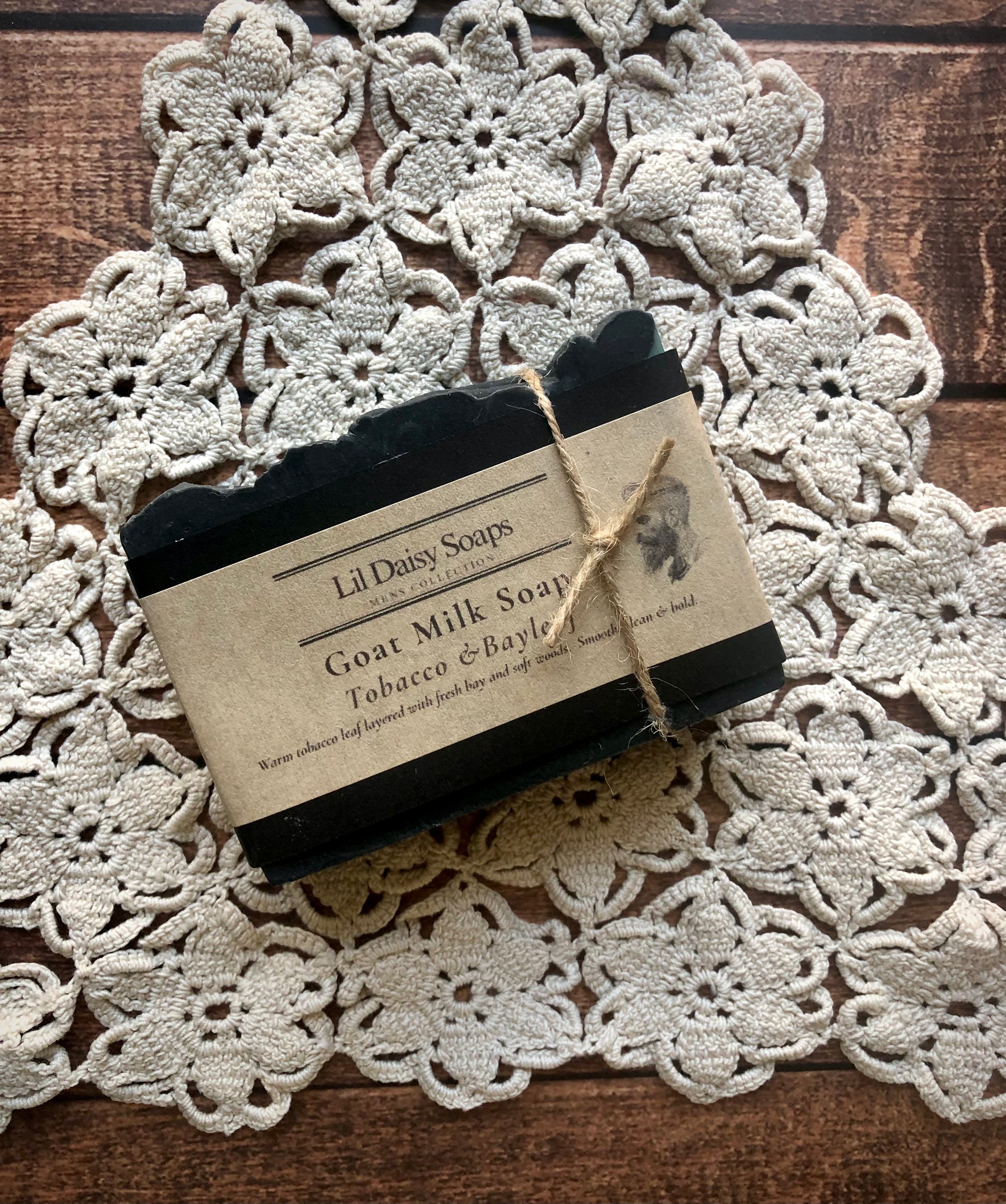 Lil Daisy Soaps Tobacco & Bayleaf Natural Goat Milk Soap Bar wrapped in kraft paper on a crochet doily.