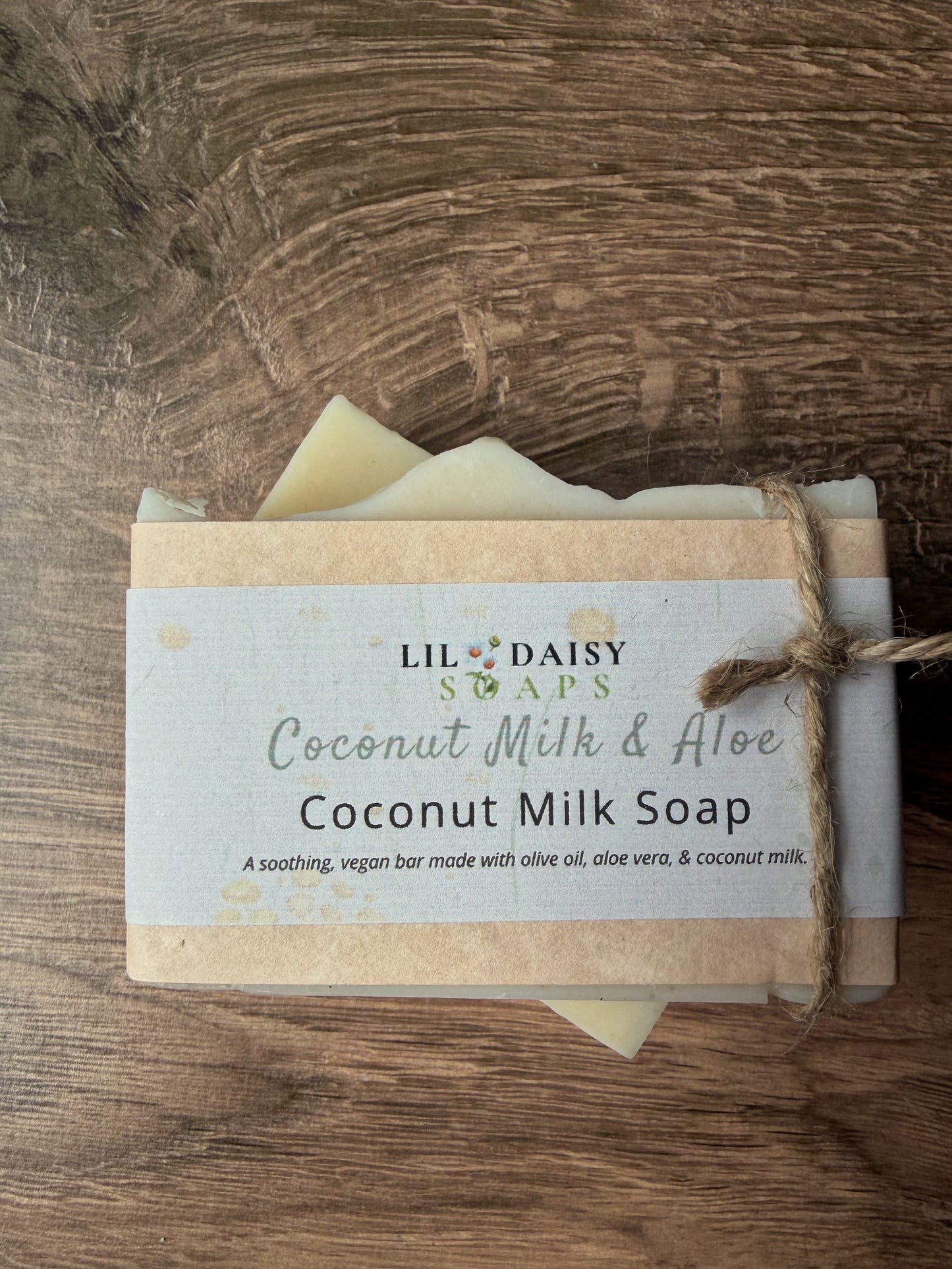 A Lil Daisy Soaps Unscented Coconut Milk & Aloe Soap Bar, wrapped in a label and tied with twine.