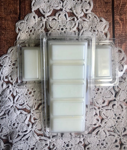 A Lil Daisy Soaps Vanilla Chai Latte Snap Bar Wax Melt on wood with a clamshell of wax melts on a lace doily.