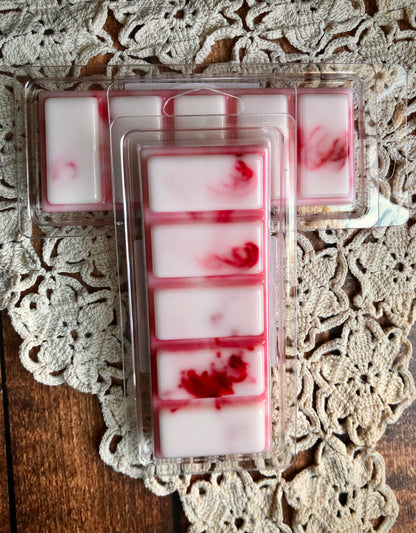 A Lil Daisy Soaps Winterberry Woods Snap Bar Wax Melt sits on a doily, bringing festive fragrance home.
